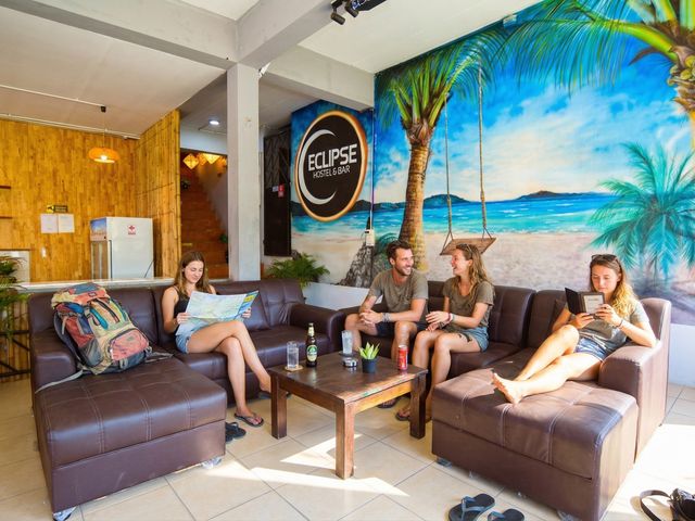 Backpackers relaxing on Eclipse lounge sofas with beach mural and Eclipse logo